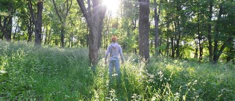 A young guy in a gray sports suit stands opposite the sun among photo