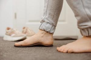 Flat feet diagnosis and orthotics, shoe inserts. Problems with flatfoot, pain. Identification of flat foot. Treatment to plantar fasciitis. Womans foot and insoles at home, close up view. photo