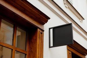 Blank signboard mock up, on the facade. Copy space for your store sign or logo. Modern empty outdoor signage, mockup to add company logo. Black square store signboard on white wall. photo