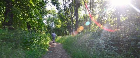 A young guy in a gray sports suit runs along the path among the photo