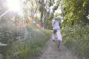 A young guy in a gray sports suit runs along the path among the photo