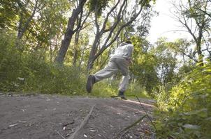 A young guy in a gray sports suit runs along the path among the photo