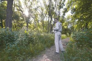 un joven con un traje deportivo gris está parado con una botella de w foto