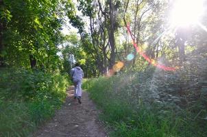 A young guy in a gray sports suit runs along the path among the photo