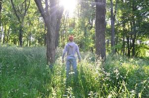 A young guy in a gray sports suit stands opposite the sun among photo