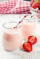 Strawberry milkshake in the glass jar on white wooden background photo