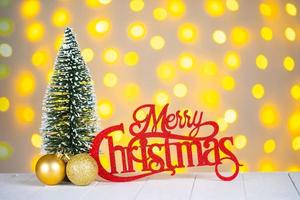 Christmas tree, golden balls and red wooden lettering Merry Christmas on light bokeh background. photo