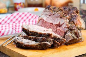 Baked pork meat with spices on brown wooden cutting board photo