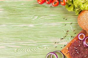 The ingredients for the burger on green wooden background photo