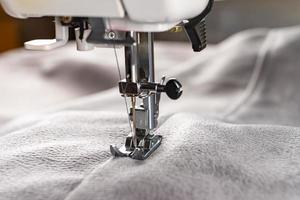 Modern sewing machine and gray fabric. Sewing process, handmade, hobby, DIY, business, repair photo