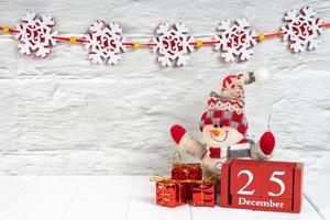 Decorative christmas tree, gift boxes and wooden calendar on white wooden background. photo