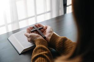 Woman sitting and studying the scriptures.The  wooden cross in the hands. Christian education concepts The Holy Scriptures open and pray photo