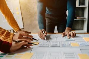 UX developer and ui designer brainstorming about mobile app interface wireframe design with customer breif and color code at modern office. photo