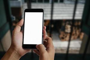 una mano de mujer sosteniendo un dispositivo de teléfono inteligente en la cafetería o café foto