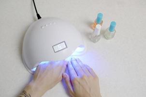 Hands of young woman at manicure procedure close up on white background photo