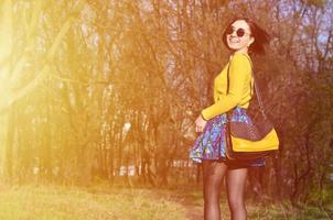 A joyful girl in a bright yellow sweater walks through the sprin photo