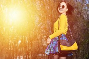 A joyful girl in a bright yellow sweater walks through the sprin photo