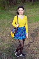 A joyful girl in a bright yellow sweater walks through the sprin photo