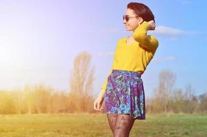 Attractive and cute Brunette girl in a yellow sweater walks thro photo