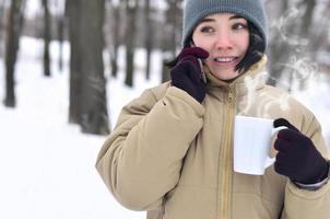 Winter portrait of young girl with smartphone and coffee cup photo