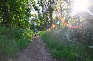 A young guy in a gray sports suit runs along the path among the photo