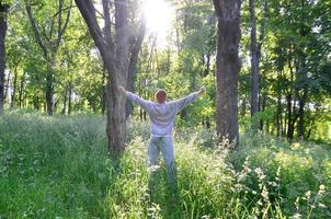 A young guy in a gray sports suit rejoices in the rising of the photo