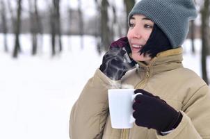 Winter portrait of young girl with smartphone and coffee cup photo