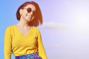 Attractive and cute Brunette girl in a yellow sweater against a photo