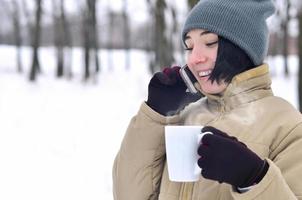 Winter portrait of young girl with smartphone and coffee cup photo