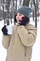 retrato invernal de una joven con smartphone y taza de café foto