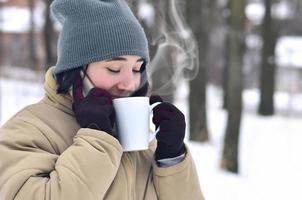 Winter portrait of young girl with smartphone and coffee cup photo