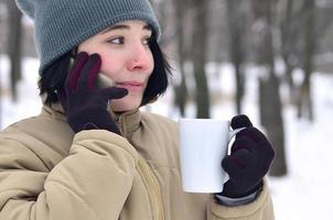 retrato invernal de una joven con smartphone y taza de café foto