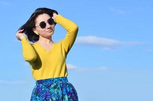 Attractive and cute Brunette girl in a yellow sweater against a photo