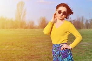 Attractive and cute Brunette girl in a yellow sweater walks thro photo