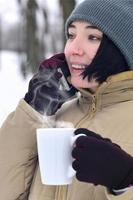 retrato invernal de una joven con smartphone y taza de café foto