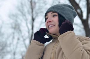 Winter portrait of young girl with smartphone photo