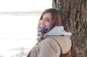 una joven y sonriente niña caucásica mira alrededor de la línea del horizonte entre el cielo y el lago congelado en invierno foto