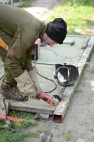 Electric wheel grinding on steel structure outdoors. Old manual worker in protective gloves cutting metal door with grinder photo