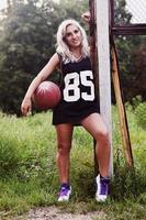 Young blonde girl with orange basketball posing outdoors photo