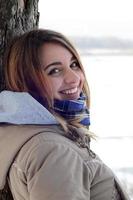 A young and smiling Caucasian girl looks around the horizon line between the sky and the frozen lake in winter time photo