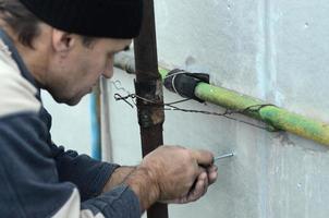 An elderly worker creates holes in the expanded polystyrene wall for the subsequent drilling and installation of an umbrella dowel. The process of fixing expanded polystyrene plates. Insulation work photo