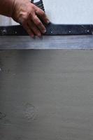 Hands of an old manual worker with wall plastering tools renovating house. Plasterer renovating outdoor walls and corners with spatula and plaster. Wall insulation. Construction finishing works photo