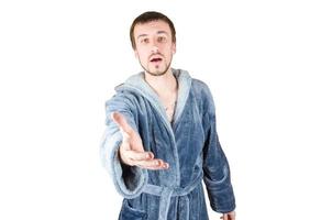 Portrait of young caucasian bearded man in blue bathrobe inviting to come isolated on white background photo