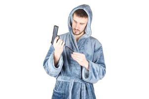 Portrait of young caucasian bearded man in blue bathrobe with black firearm isolated on white background photo