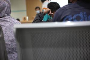 young man and many people waiting for medical and health services to the hospital, patients waiting for treatment at the hospital. photo