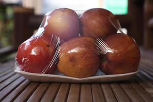 black peel with six apples wrapped in transparent plastic isolated on brown background photo