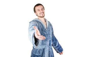 Portrait of young caucasian bearded man in blue bathrobe inviting to come isolated on white background photo