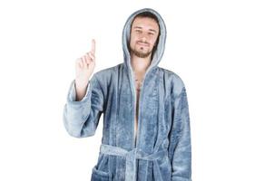 Portrait of young caucasian bearded man in blue bathrobe shows attention gesture isolated on white background photo