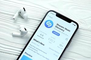 KHARKOV, UKRAINE - MARCH 5, 2021 Shazam icon and application from App store on iPhone 12 pro display screen with airpods pro on white table photo
