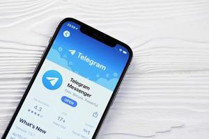 kharkov, ucrania - 5 de marzo de 2021 icono de telegram messenger y aplicación de la tienda de aplicaciones en la pantalla de visualización del iphone 12 pro en la mesa blanca foto